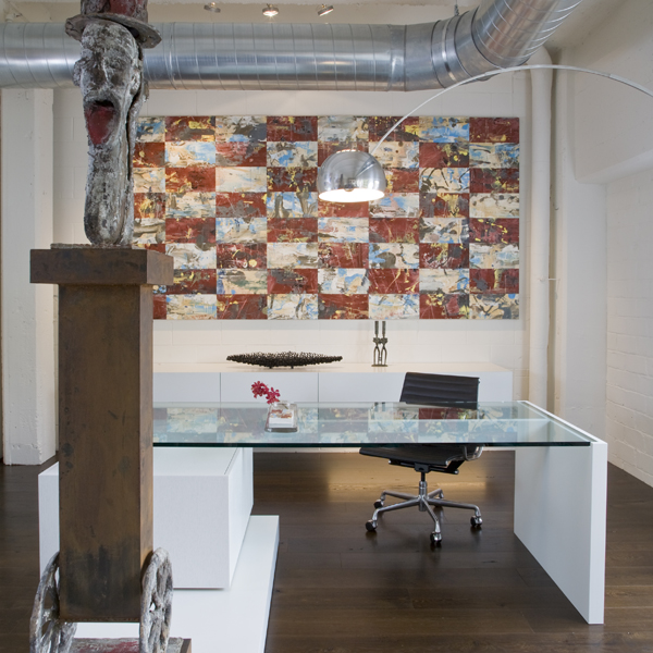 A painting by Keith Milow hangs behind a custom designed desk that integrates a pedestal for this contemporary sculpture in this Washington DC luxury loft, second home for an international power couple