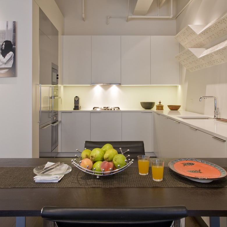 The contemporary kitchen of this luxury loft, second home for an international power couple, boasts custom designed cabinetry and a sculpture by Keith Milow