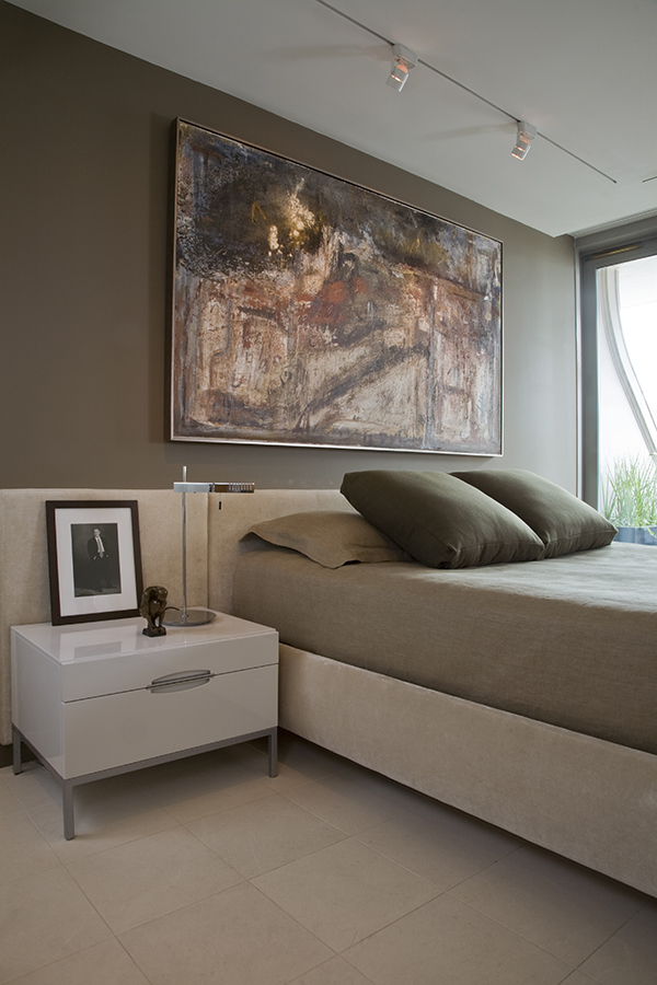 Bold colors, track lighting and an upscale upholstered bed and headboard come together in the airy and luxurious bedroom of this upscale Washington, DC condo by Architecture and Interior Design firm Studio Santalla