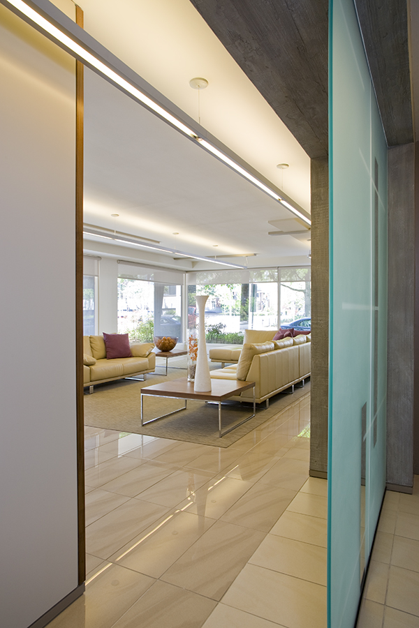 Cement paneling and frosted glass panels bathe this upscale modern condominium lobby in natural light