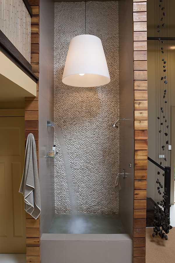 The luxurious two story shower of this sustainable home spa by Studio Santalla in Washington, DC features river rock pebbles and cedar paneling.