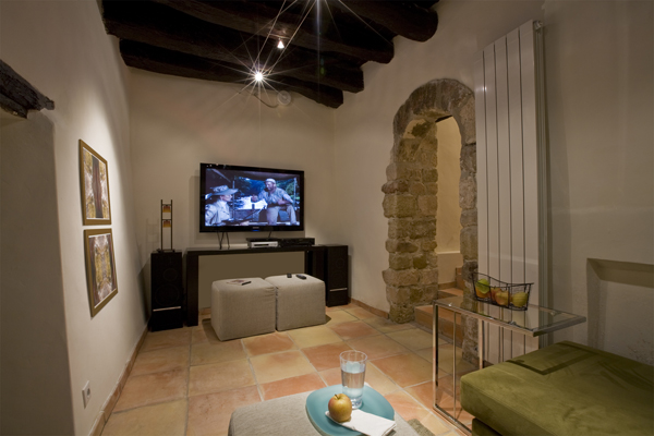 The media room of this 800 year old French town home renovation by Studio Santalla features exposed stone and roof beams.