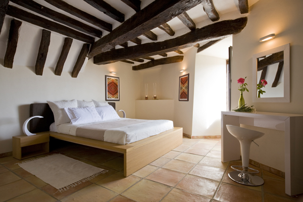 The roof beams in the bedroom of this 800 year old French home have been left exposed in the renovation by Washington, DC architect and interior design firm Studio Santalla