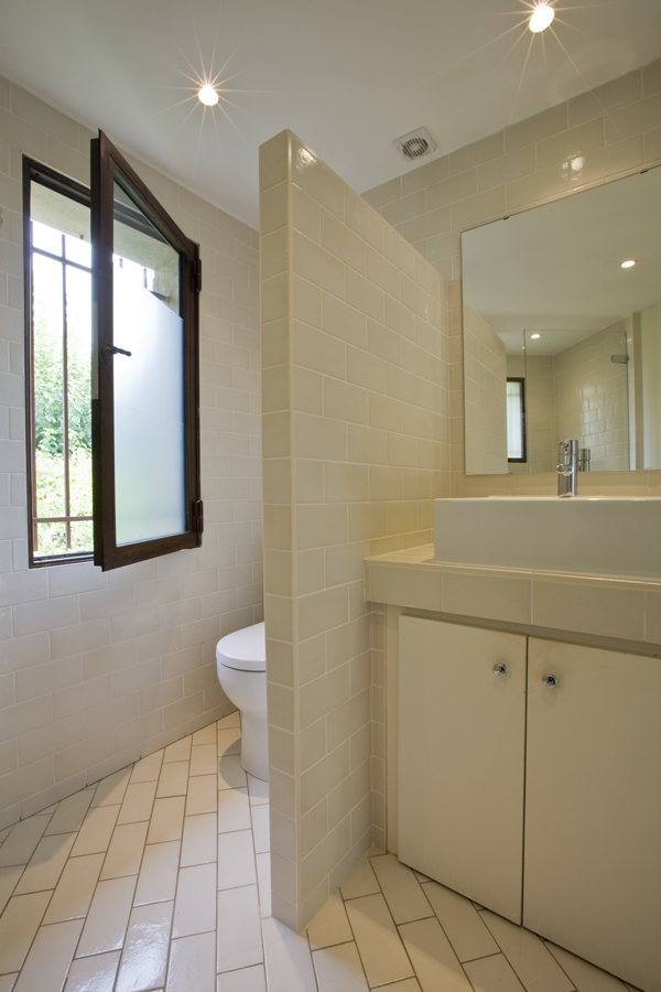 A partial wall conceals the toilet in this bathroom renovation by Georgetown Architecture and Interior Design firm, Studio Santalla