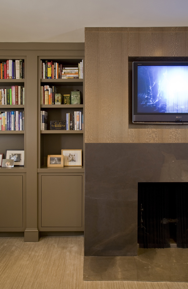 An elegant contemporary fireplace and media center are accompanied by built in bookcases in this master bedroom by DC Architecture and Interior Design firm Studio Santalla