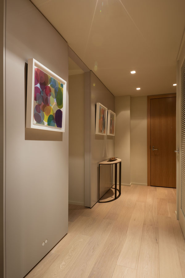 An unassuming entry way provides an elegant background for a sophisticated art collection, and hides the bedroom door.