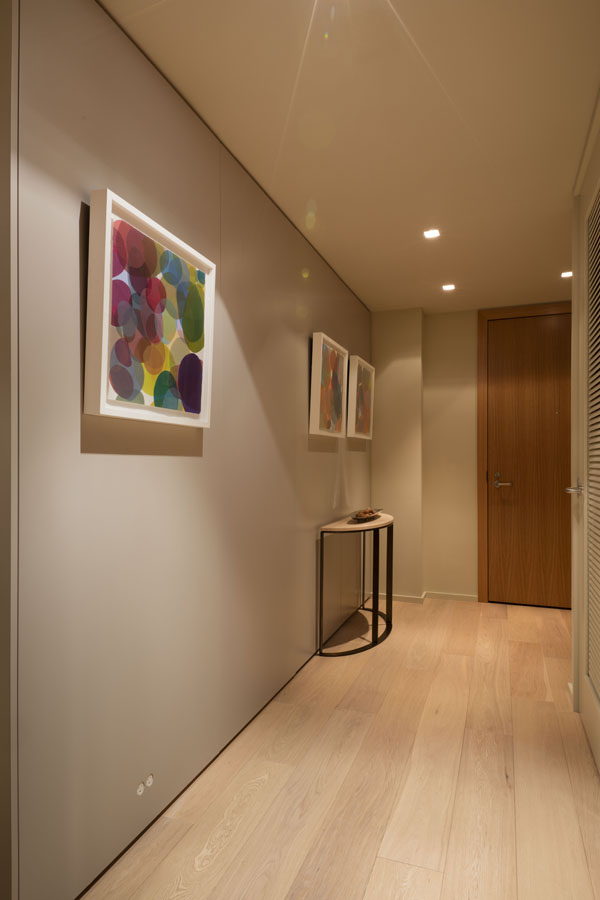 An unassuming entry way provides an elegant background for a sophisticated art collection, and hides the bedroom door.